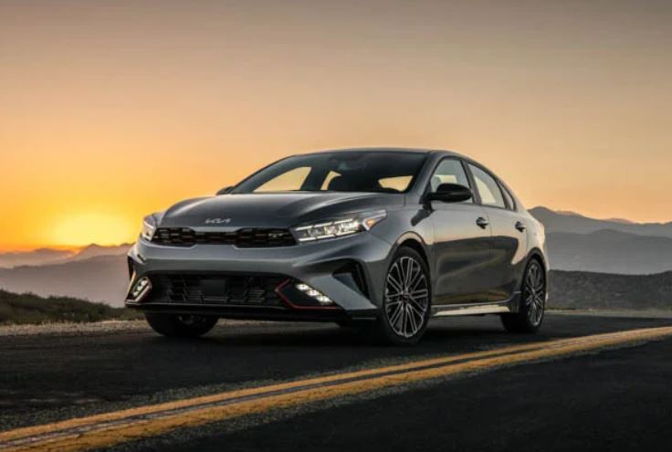 A silver 2022 Kia Forte parked on the highway with the sun setting in the background. | Kia dealer in Conway, AR.