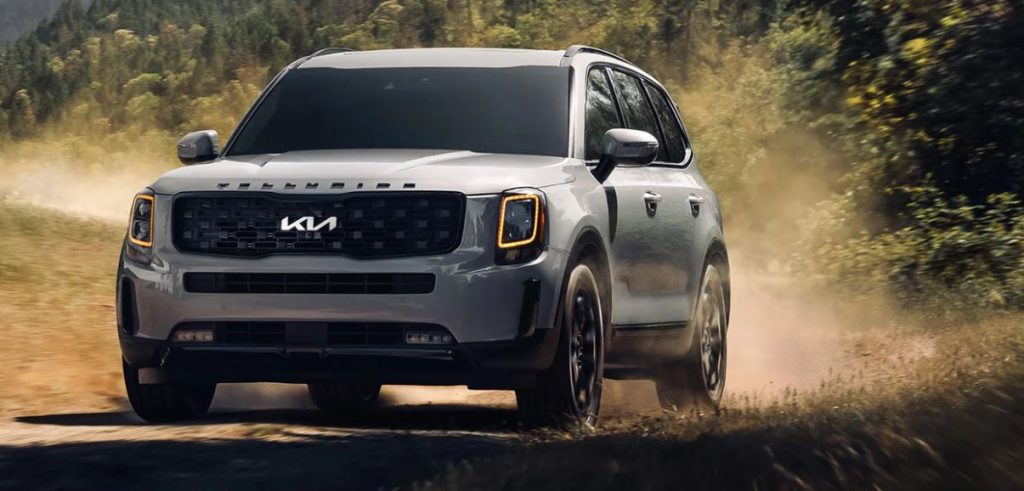 A silver 2022 Kia Telluride bring driven on a dirt road with trees in the background. | Kia dealer in Conway, AR.