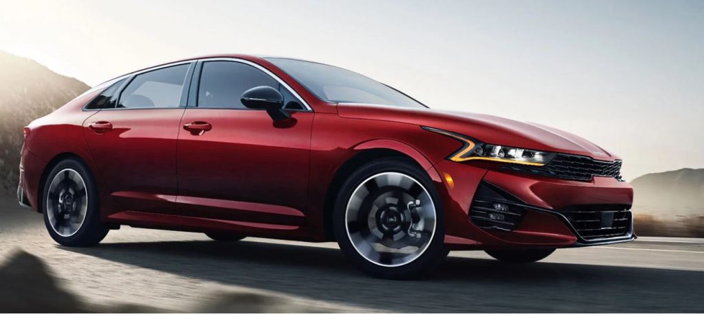 Profile view of a red 2022 Kia K5 being driven. | Kia service in Conway, AR.