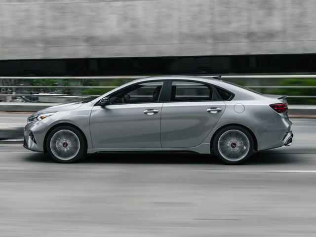 Profile view of a silver 2023 Kia Forte being driven on the highway. | Kia dealer in Conway, AR.