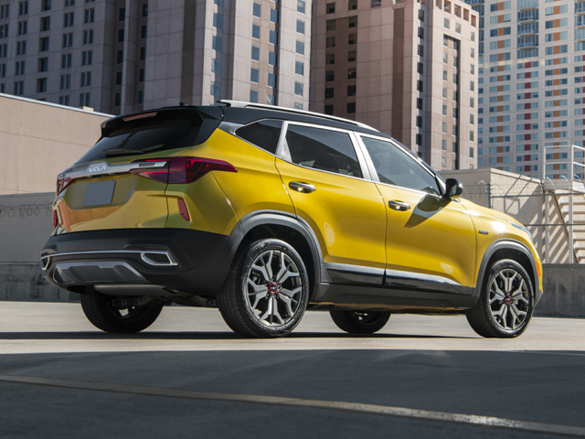 Rear profile view of a yellowish-gold 2023 Kia Seltos parked with buildings in the background. | Kia dealer in Conway, AR.